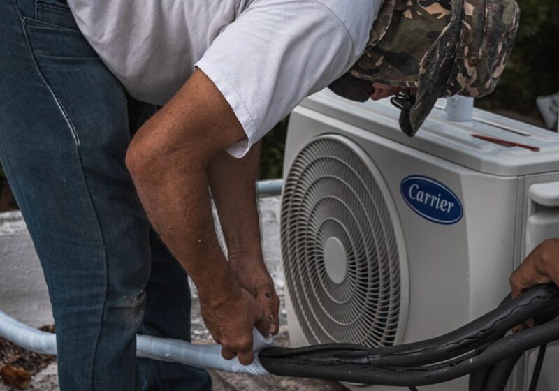 HVAC technician repairing an outdoor air conditioner condenser unit